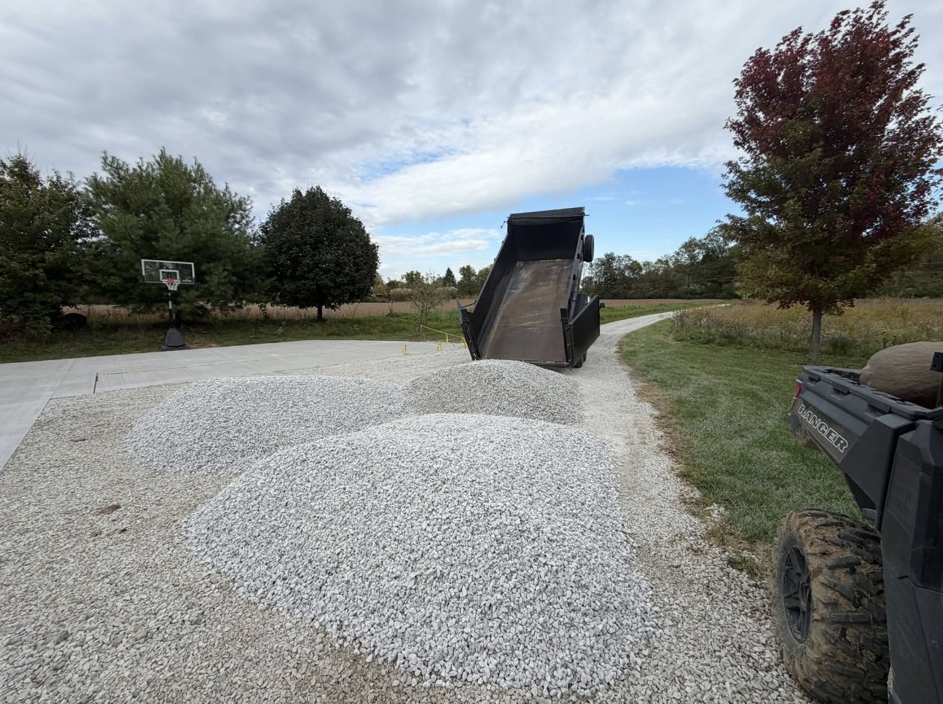 Gravel being placed by a dump trailer on a property